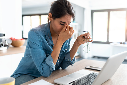 business woman Shot of stressed business woman working from home on laptop looking worried, tired and overwhelmed.